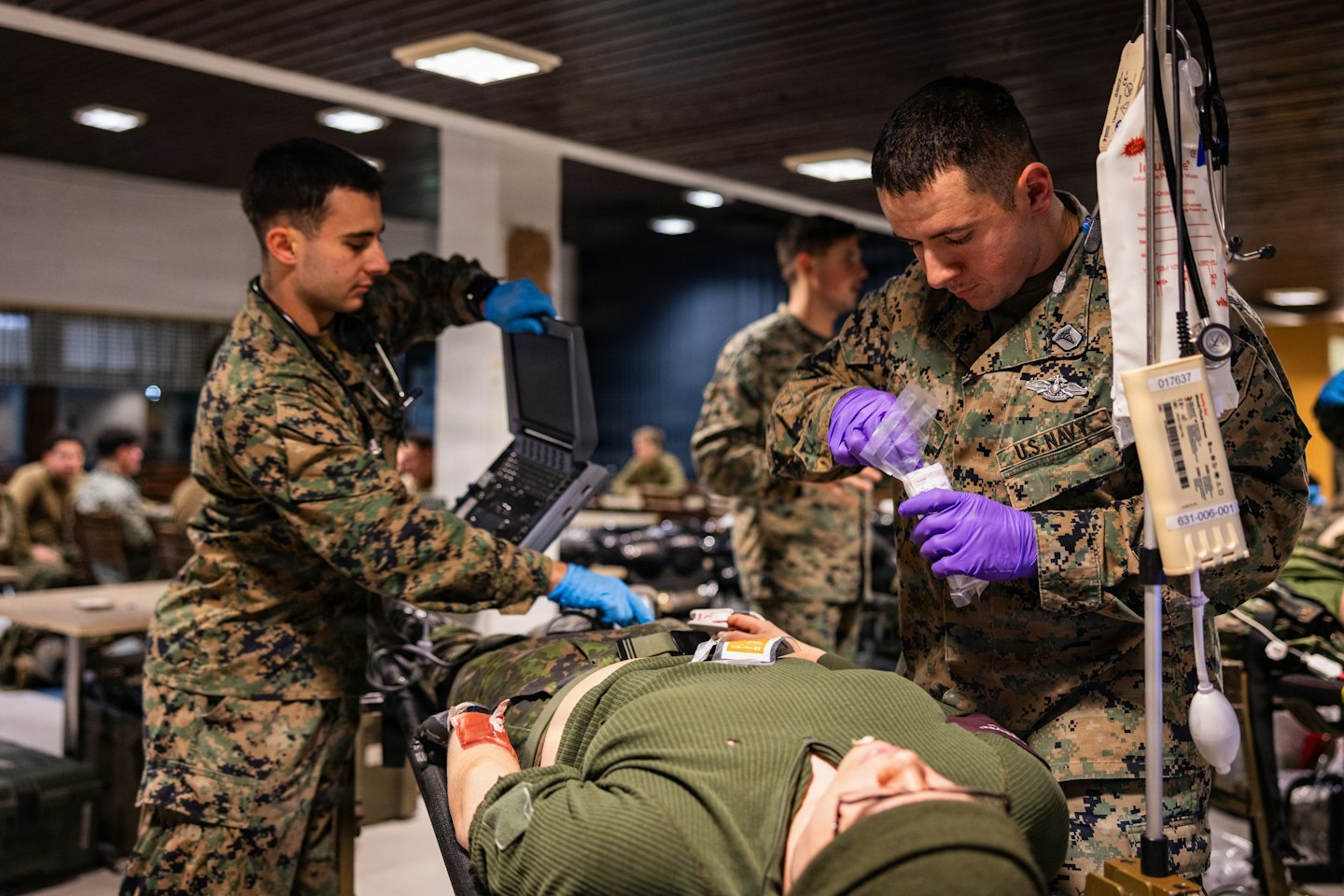Dos técnicos médicos preparan equipo para un paciente en una camilla.
